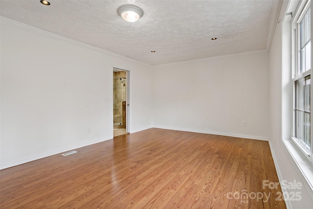 unfurnished room featuring visible vents, wood finished floors, and ornamental molding