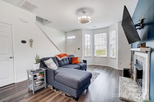 living room featuring a fireplace, visible vents, dark wood-style flooring, and baseboards