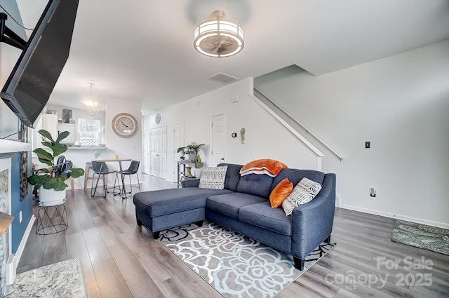 living area with a chandelier, baseboards, and wood finished floors