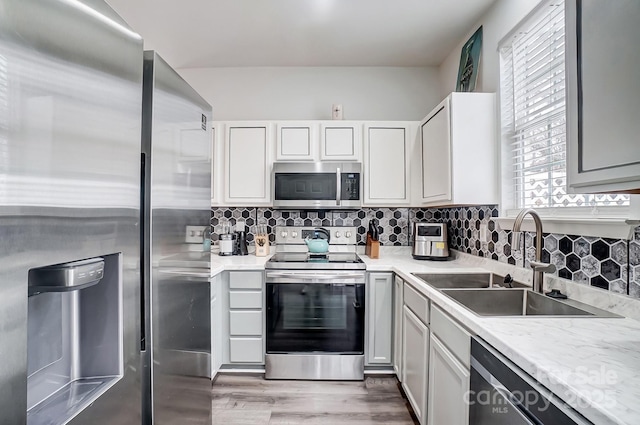 kitchen with tasteful backsplash, appliances with stainless steel finishes, light countertops, and a sink