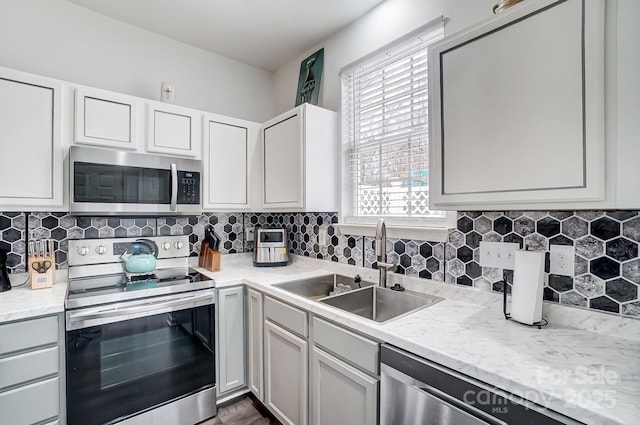 kitchen featuring a sink, stainless steel appliances, tasteful backsplash, and white cabinetry