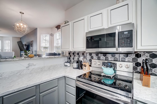 kitchen with hanging light fixtures, backsplash, gray cabinets, and appliances with stainless steel finishes