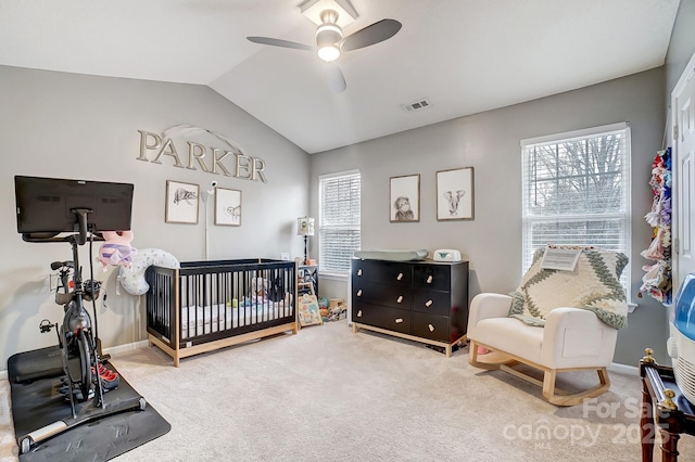 carpeted bedroom featuring visible vents, multiple windows, a crib, and lofted ceiling