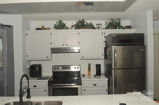 kitchen with a sink, light countertops, under cabinet range hood, appliances with stainless steel finishes, and white cabinetry