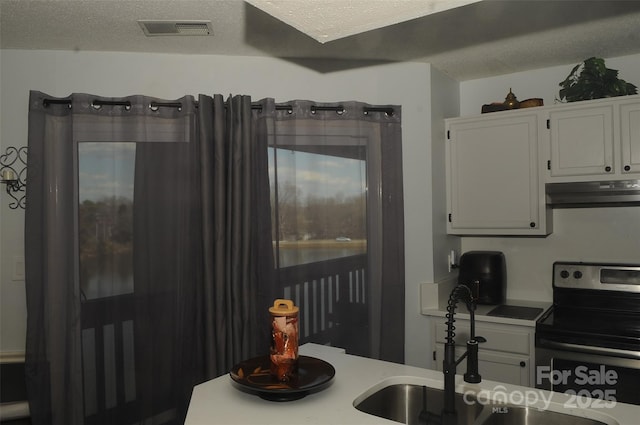 kitchen featuring visible vents, white cabinetry, under cabinet range hood, stainless steel electric stove, and a textured ceiling