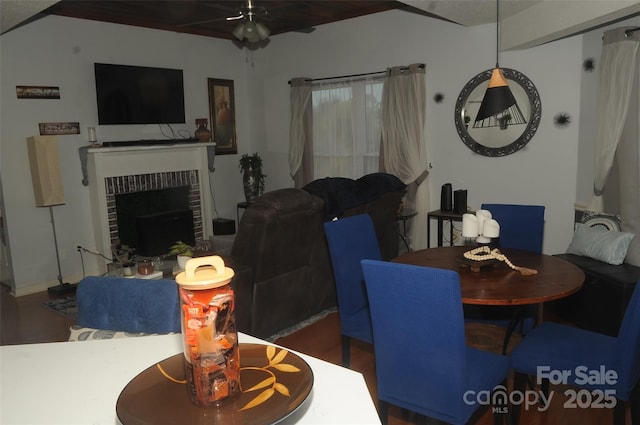 dining space featuring a brick fireplace, wood finished floors, and a ceiling fan