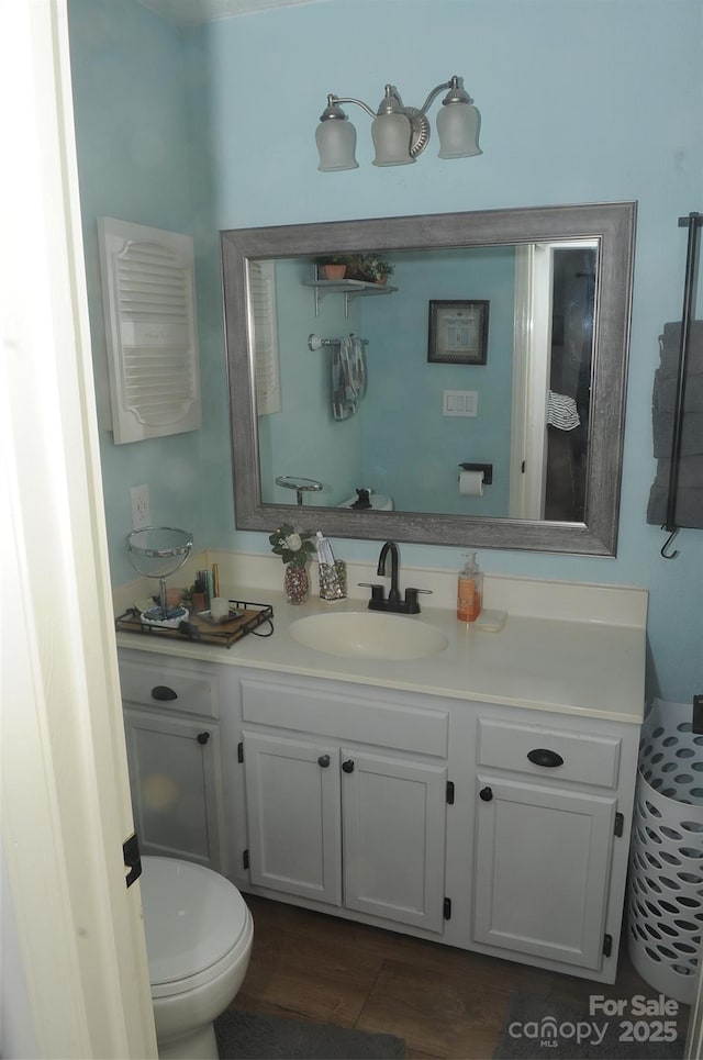 bathroom with toilet, vanity, and wood finished floors