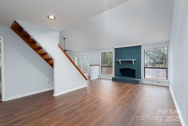 unfurnished living room featuring baseboards, a ceiling fan, wood finished floors, and stairs