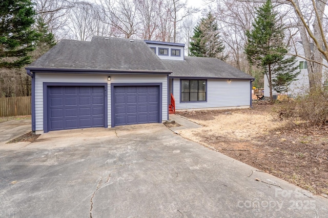 view of front of home featuring a garage, fence, and a shingled roof