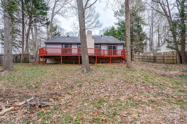 rear view of property featuring a wooden deck, a chimney, and fence