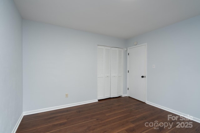 unfurnished room featuring dark wood-type flooring and baseboards