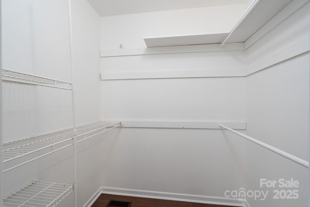 walk in closet with dark wood finished floors and visible vents