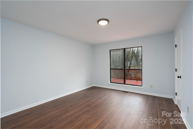 empty room with baseboards and dark wood-style floors