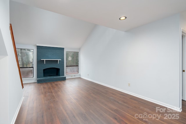 unfurnished living room with dark wood-type flooring, recessed lighting, a fireplace, baseboards, and vaulted ceiling