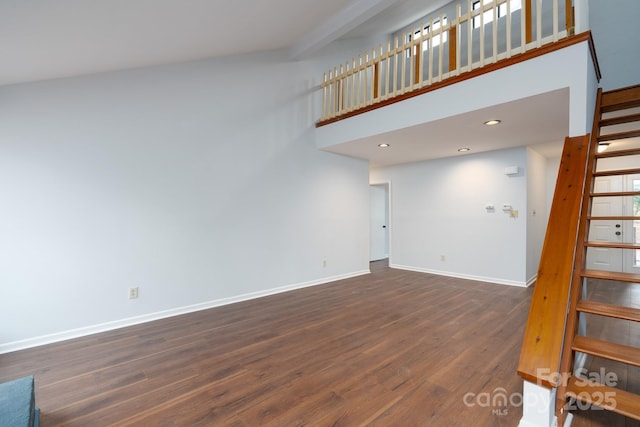 staircase with recessed lighting, a high ceiling, baseboards, and wood finished floors