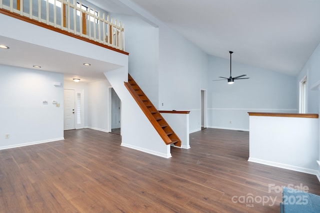 unfurnished living room with high vaulted ceiling, dark wood-style floors, baseboards, and ceiling fan