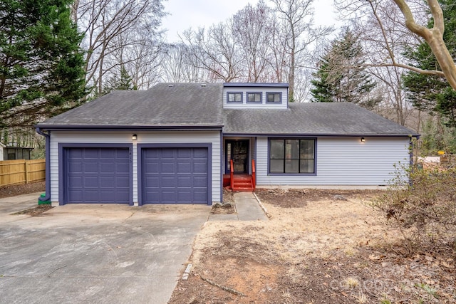 mid-century inspired home with fence, a garage, driveway, and roof with shingles