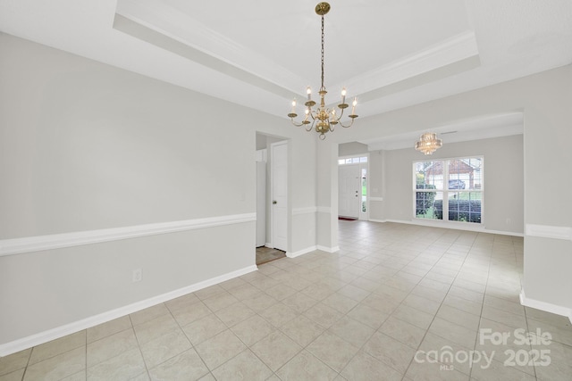 empty room featuring a notable chandelier, a raised ceiling, and baseboards