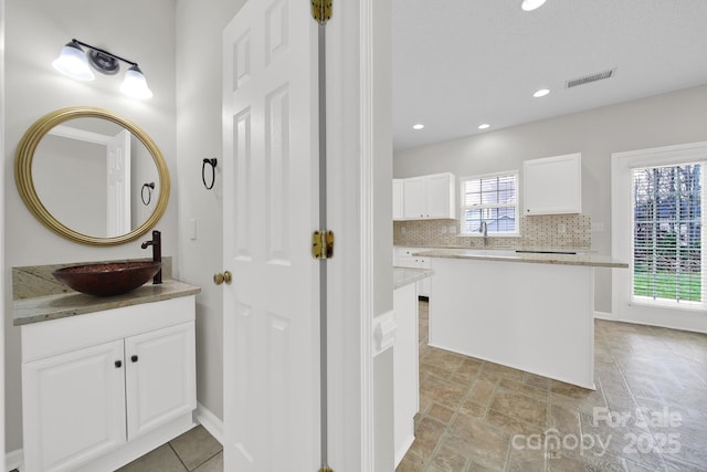 bathroom featuring vanity, recessed lighting, visible vents, and backsplash