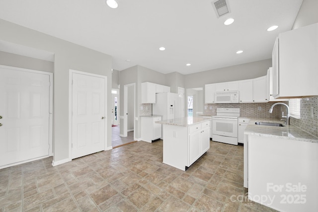 kitchen with visible vents, a sink, backsplash, white cabinetry, and white appliances