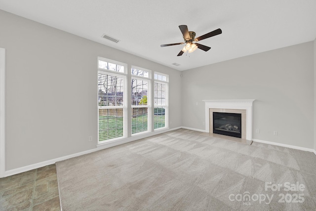 unfurnished living room with visible vents, baseboards, ceiling fan, and a premium fireplace