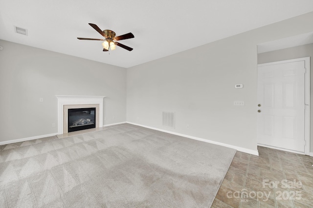 unfurnished living room featuring visible vents, baseboards, ceiling fan, and a glass covered fireplace