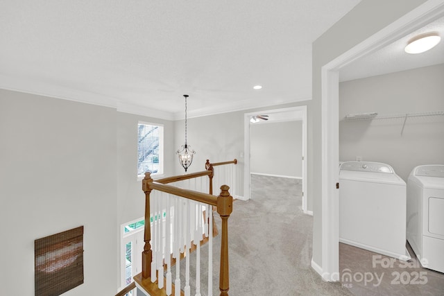 hallway featuring an upstairs landing, washing machine and dryer, an inviting chandelier, carpet flooring, and baseboards