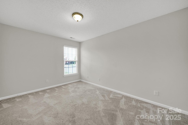 carpeted empty room with visible vents, a textured ceiling, and baseboards