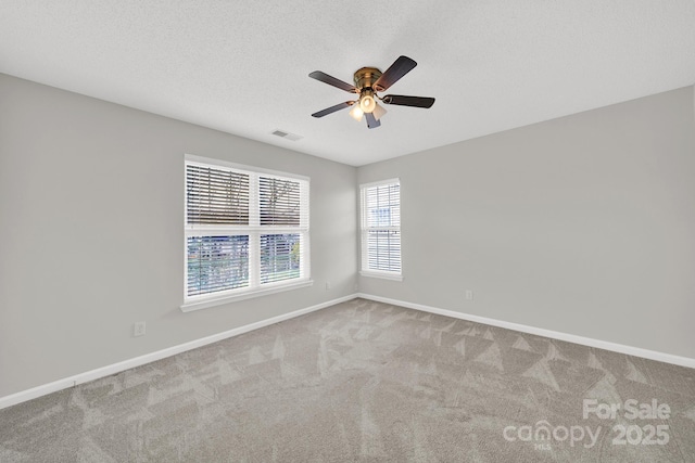 carpeted empty room featuring visible vents, baseboards, a textured ceiling, and a ceiling fan