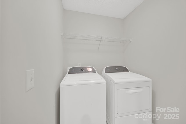 laundry area with laundry area, washing machine and dryer, and a textured ceiling