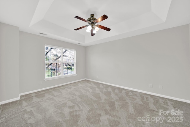 spare room with visible vents, baseboards, carpet, and a tray ceiling