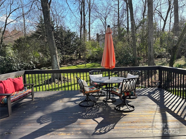 wooden deck featuring outdoor dining area and a lawn