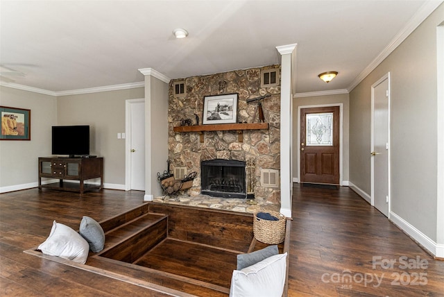 living room with wood finished floors, visible vents, baseboards, a stone fireplace, and crown molding