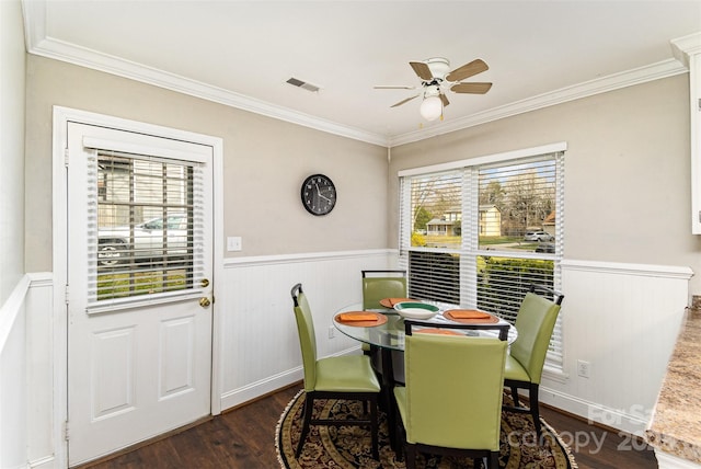 dining area featuring visible vents, a wainscoted wall, a ceiling fan, wood finished floors, and crown molding