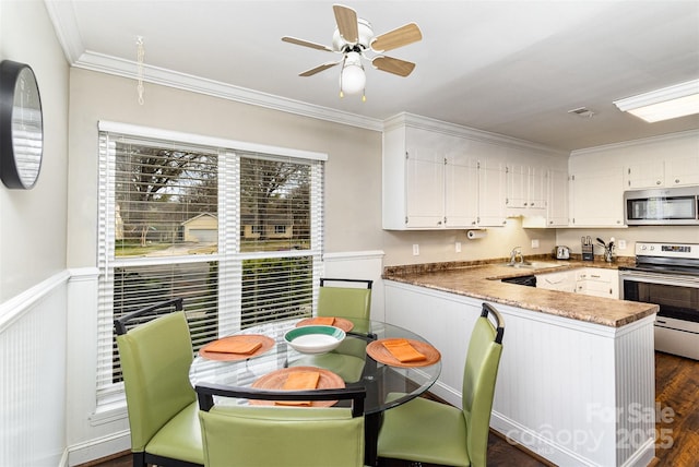 kitchen with white cabinetry, stainless steel appliances, crown molding, and a peninsula