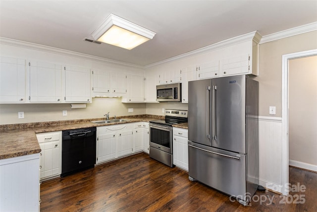 kitchen with dark wood-type flooring, ornamental molding, a sink, white cabinetry, and stainless steel appliances