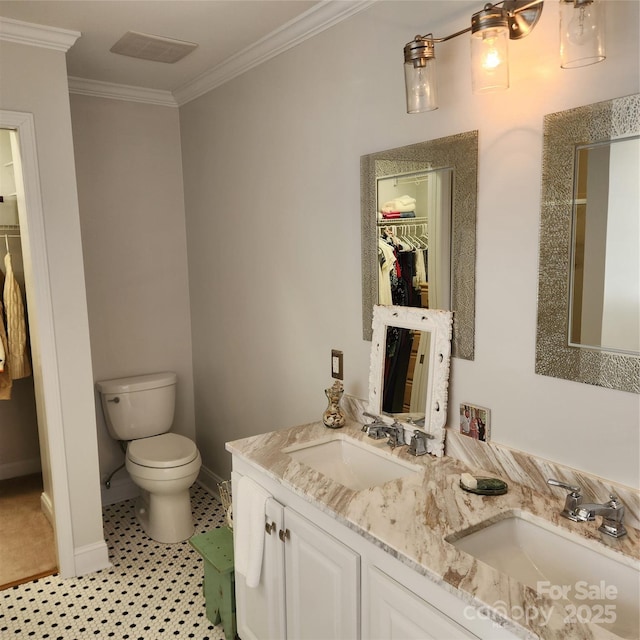 bathroom with toilet, a walk in closet, ornamental molding, and a sink