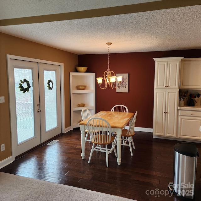 dining space featuring dark wood finished floors, a chandelier, french doors, and a textured ceiling