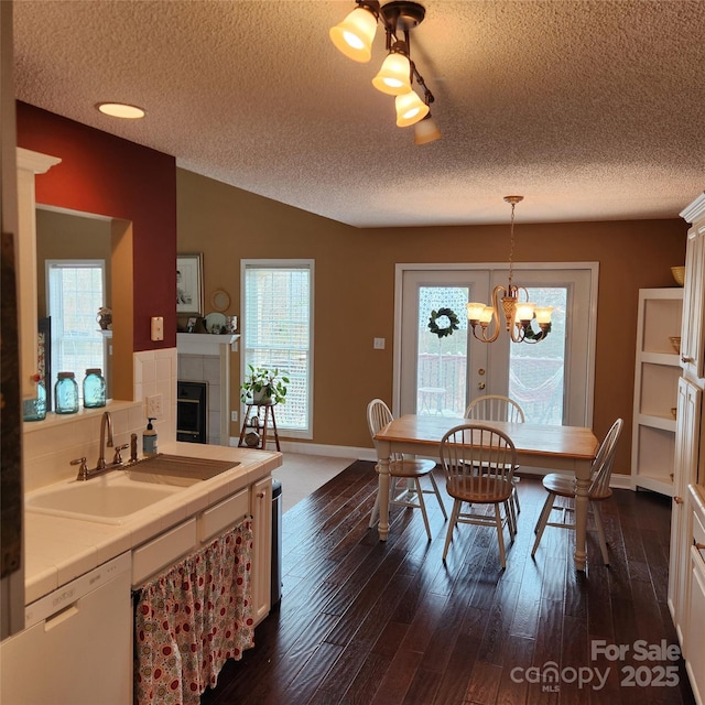 dining space featuring a chandelier, lofted ceiling, a tile fireplace, dark wood-style floors, and a textured ceiling