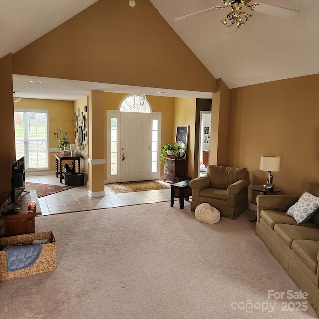 tiled entryway featuring a ceiling fan, carpet, and high vaulted ceiling