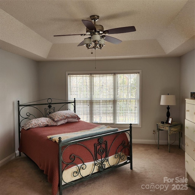 bedroom with multiple windows, a raised ceiling, and carpet floors