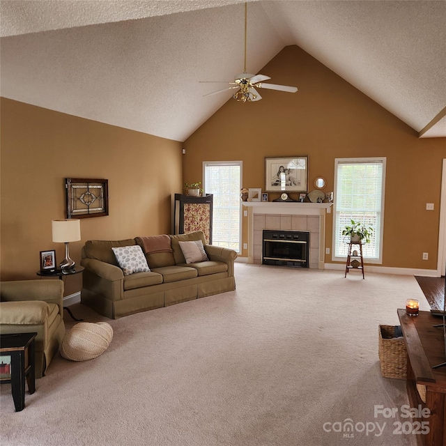 living area with a tiled fireplace, plenty of natural light, a textured ceiling, and carpet floors