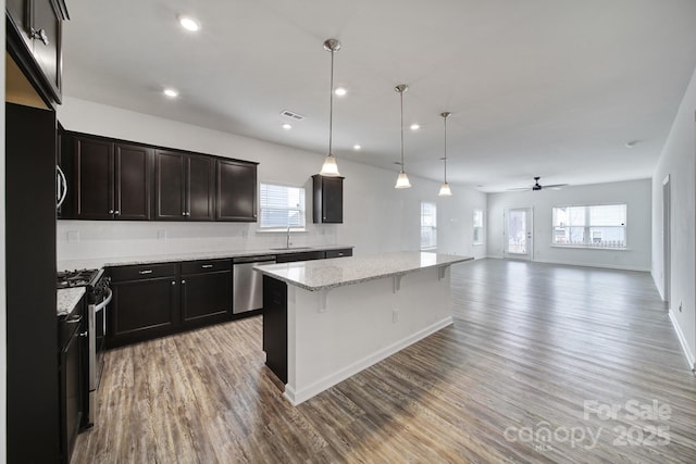 kitchen with a ceiling fan, light wood-type flooring, appliances with stainless steel finishes, and a center island