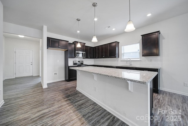 kitchen featuring a sink, tasteful backsplash, a center island, stainless steel appliances, and dark brown cabinets