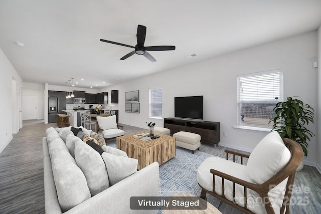 living room with baseboards, wood finished floors, and a ceiling fan