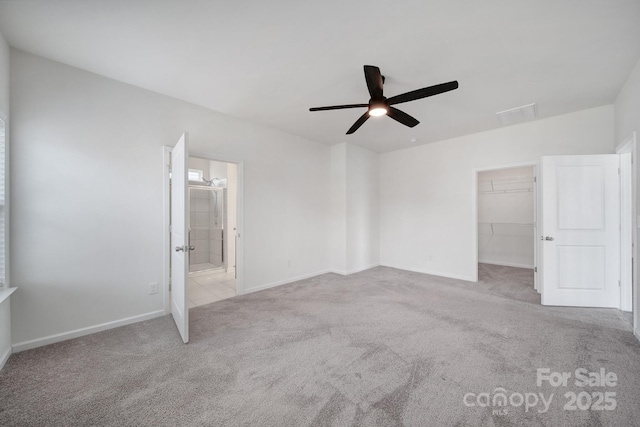 unfurnished bedroom featuring a spacious closet, carpet flooring, baseboards, and ceiling fan