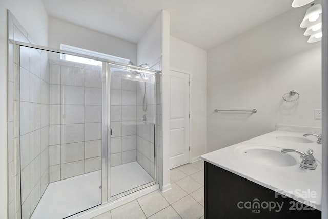 full bathroom featuring tile patterned floors, double vanity, a shower stall, and a sink