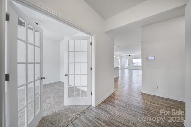 hallway featuring french doors, baseboards, and wood finished floors