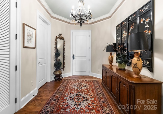 entrance foyer with baseboards, an inviting chandelier, wood finished floors, and crown molding