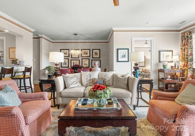 living area featuring visible vents, ceiling fan with notable chandelier, baseboards, and wood finished floors